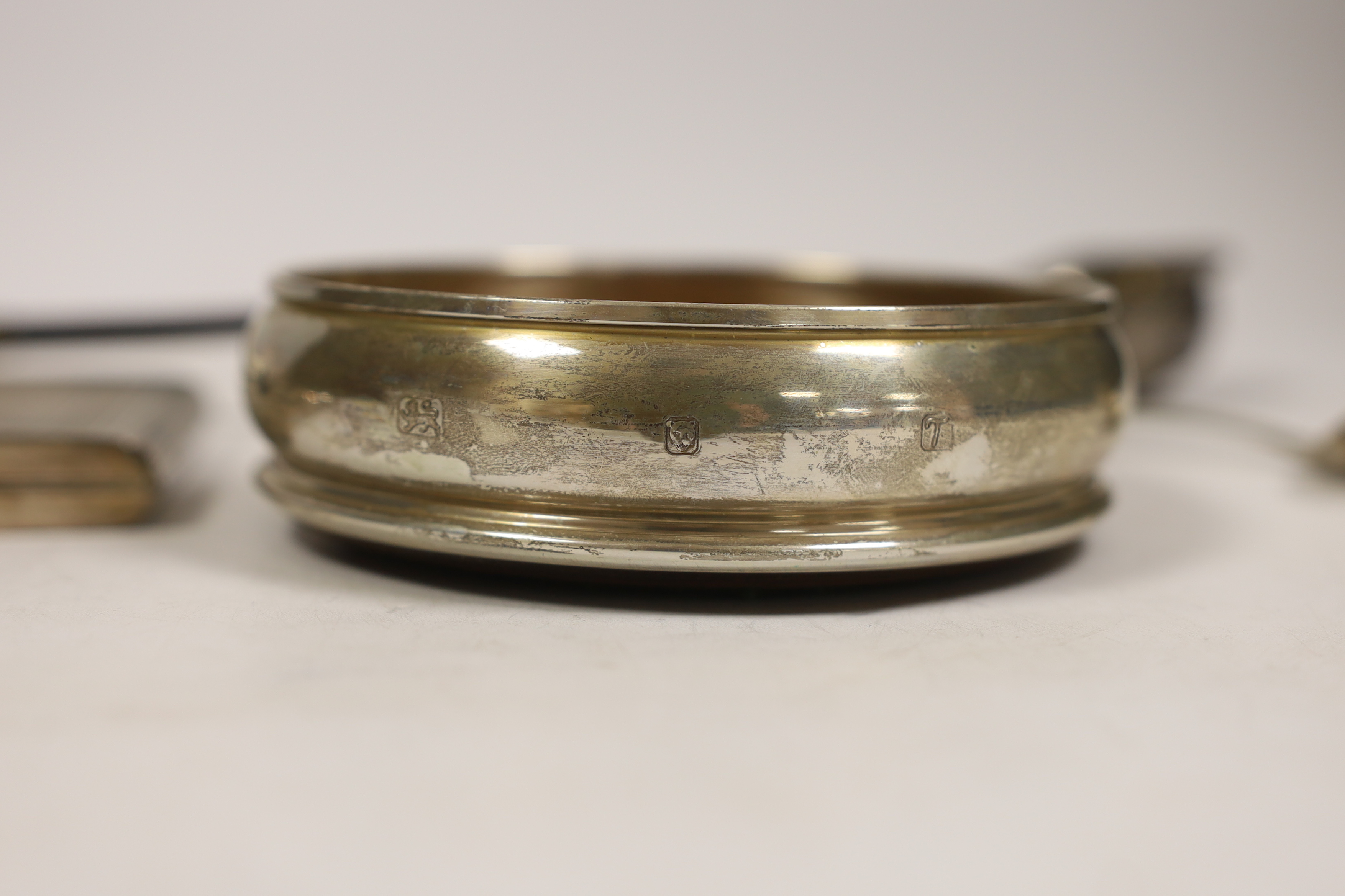 A modern silver mounted wine coaster, a silver sifter spoon, sterling cigarette case, silver tobacco box and a white metal toddy ladle with baleen handle.